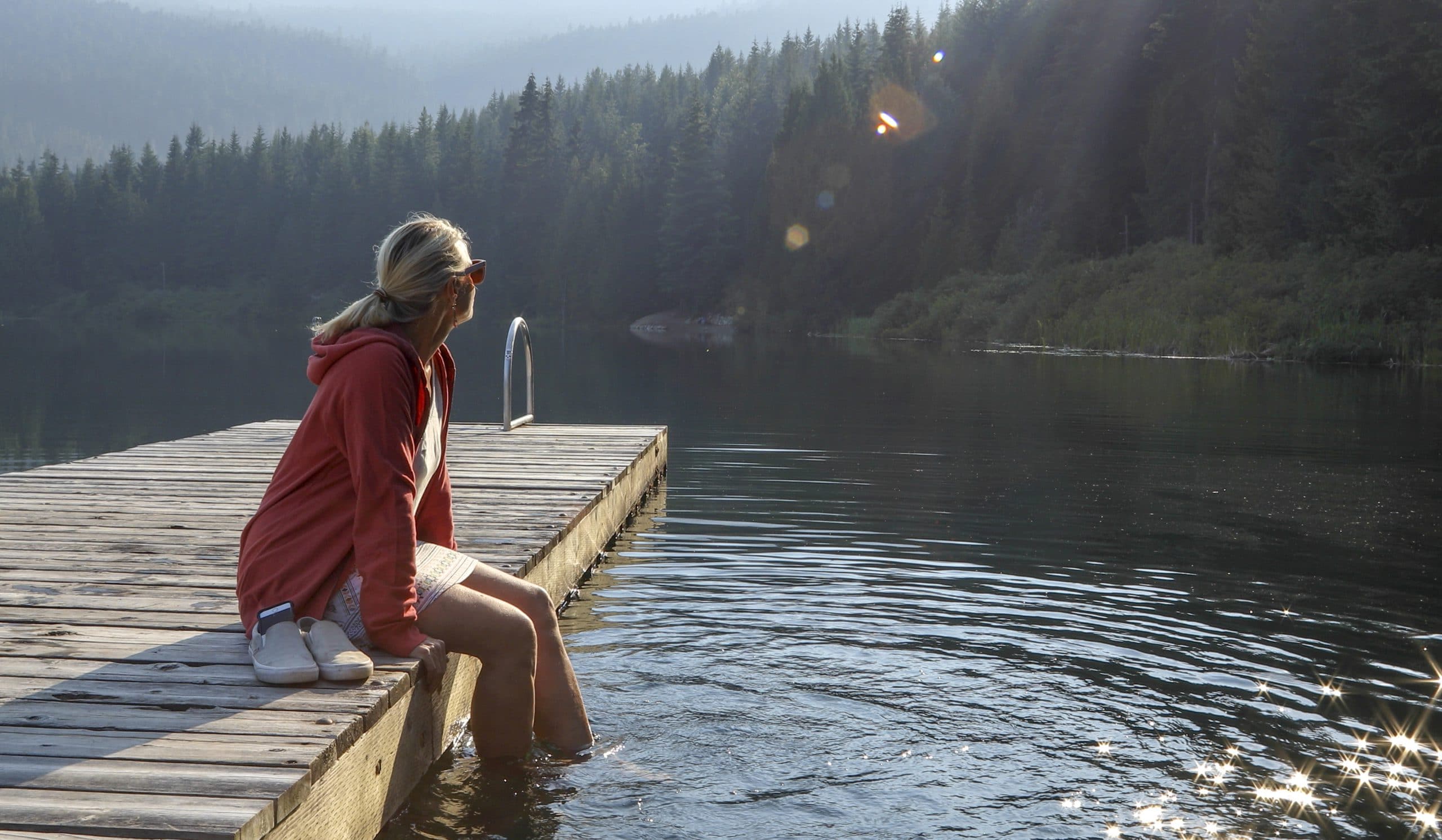 Woman sitting on dock on lake